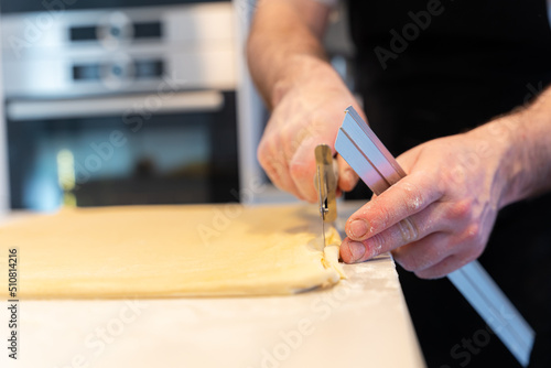 Man cooking homemade croissants, measuring puff pastry and making cuts, work at home