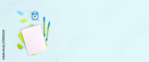 Banner. Back to school. School supplies on light blue background. Notebook, pens, alarm clock and rubber bands. Flat lay, copy space. 