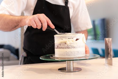Hands of a man cooking a red velvet cake at home, with the smoothing spatula leaving the perfect circle