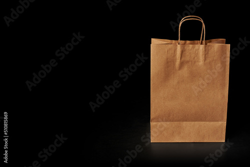 Brown paper bag insulated on a black background, front view. Delivery service advertisement.