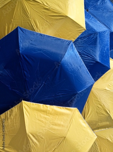 close up of stacks of folding umbrellas made of blue and yellow parachute cloth in an open state photo