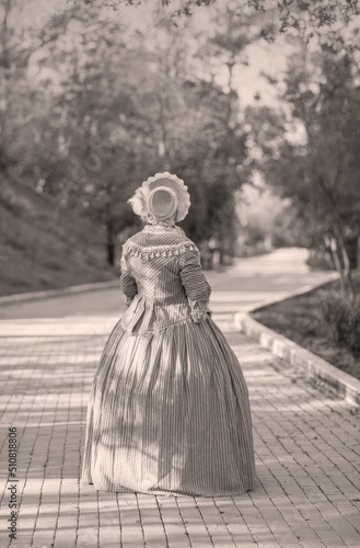 Fotografie Woman in victorian dress walking in the park. Vintage fashion.