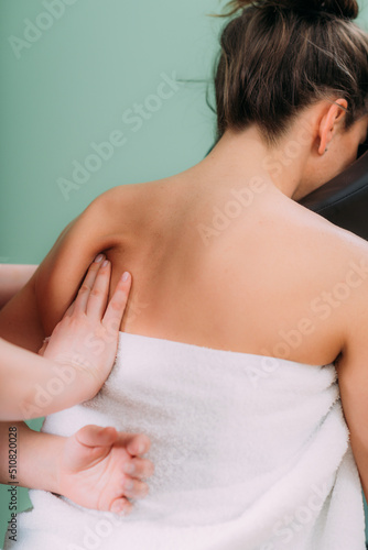 Chair Massage. Therapist massaging woman   s back in a salon  releasing muscle tension