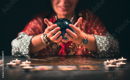 Tarot reader with tarot cards.Tarot cards face down on table near burning candles and crystal ball.