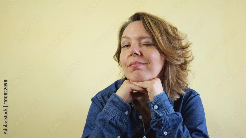 Portrait of a cheerful forty-year-old woman in a denim shirt against a light wall. Slow motion 4k Portrait of a cheerful forty-year-old woman in a denim shirt against a light wall. Slow motion 4k