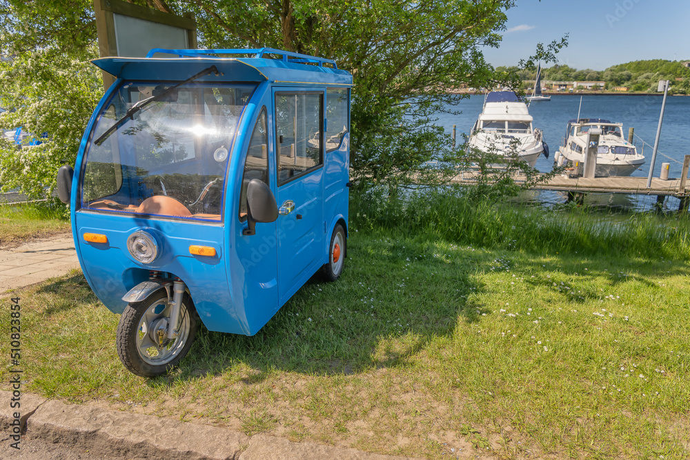 Small blue electric van placed in Sonderbord yacth harbor. Denmark