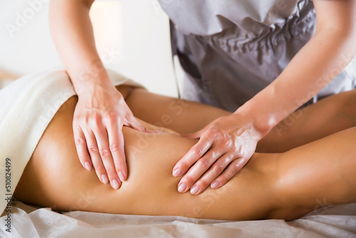 anti-cellulite thigh massage in the salon close-up. masseur doing leg massage to woman