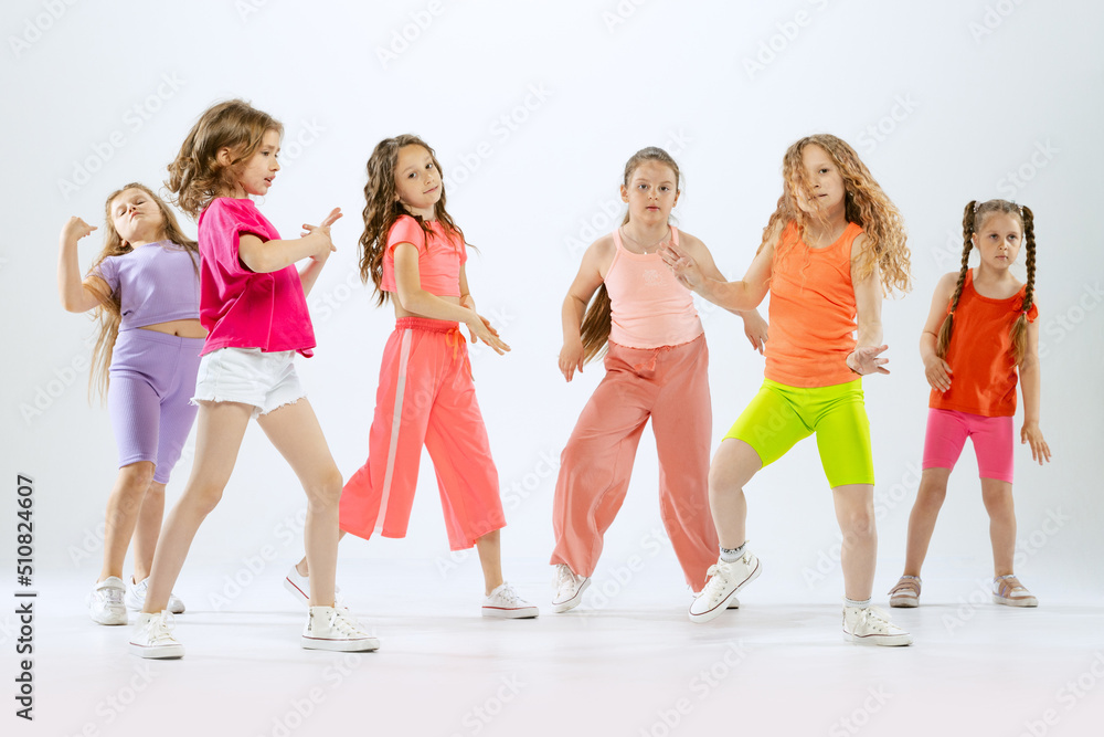 Dance group of happy, active little girls in bright colorful clothes dancing isolated on white studio background. Concept of music, fashion, art, childhood, hobby Dance group of happy, active little girls in bright colorful clothes dancing isolated on white studio background. Concept of music, fashion, art, childhood, hobby