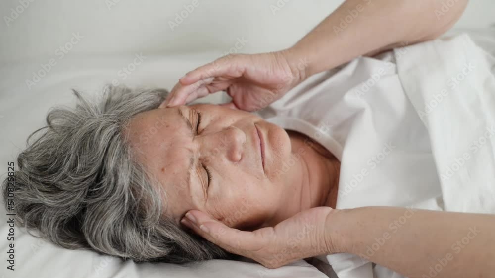 Headache, fatigue, insomnia concept. Close-up of senior woman massaging gewicht while lying on bed in bedroom. Tired elderly woman with closed eyes with pain indoors. Headache, fatigue, insomnia concept. Close-up of senior woman massaging gewicht while lying on bed in bedroom. Tired elderly woman with closed eyes with pain indoors.