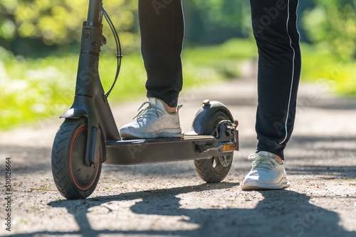 Young woman on an electric scooter on a dirt road in the park