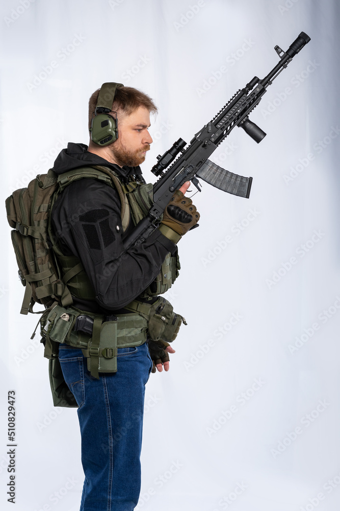 airsoft player in full gear with weapons series GG RK74 fire. a man in an outfit, in headphones, a bulletproof vest, with a backpack and a belt. White background. airsoft player in full gear with weapons series GG RK74 fire. a man in an outfit, in headphones, a bulletproof vest, with a backpack and a belt. White background.