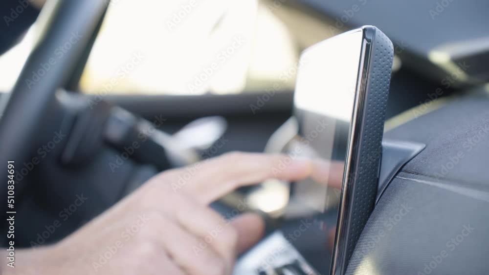 A man works on the touchscreen system on the dashboard in a car - side closeup A man works on the touchscreen system on the dashboard in a car - side closeup