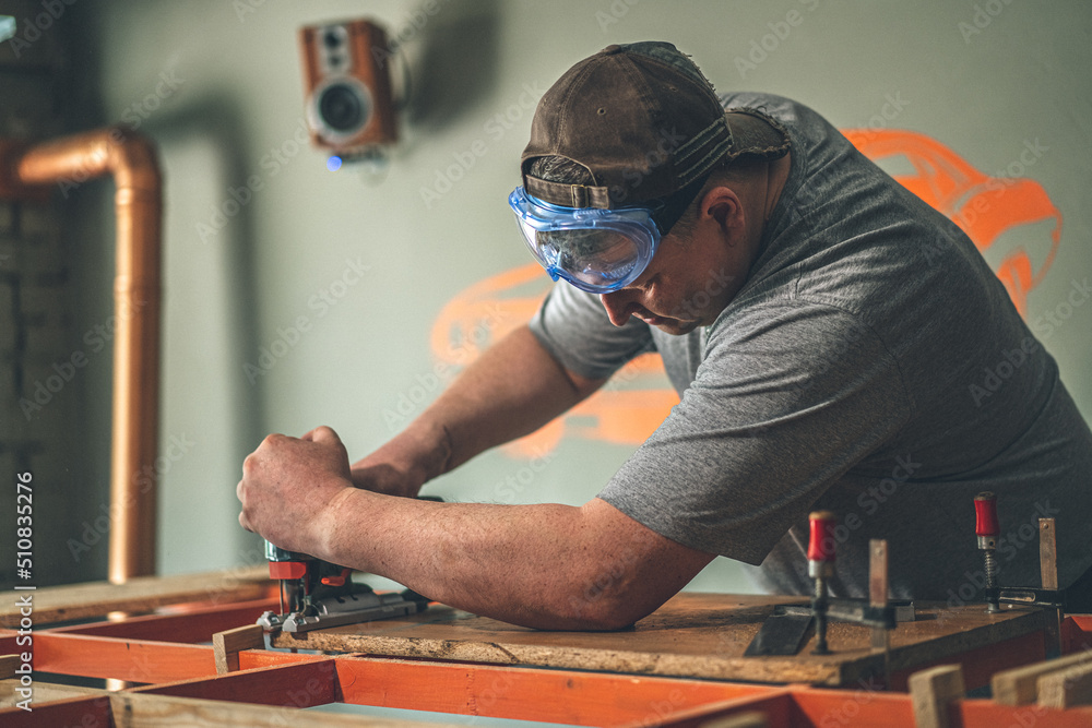 Carpenter sawing wood with an electric jigsaw. small business