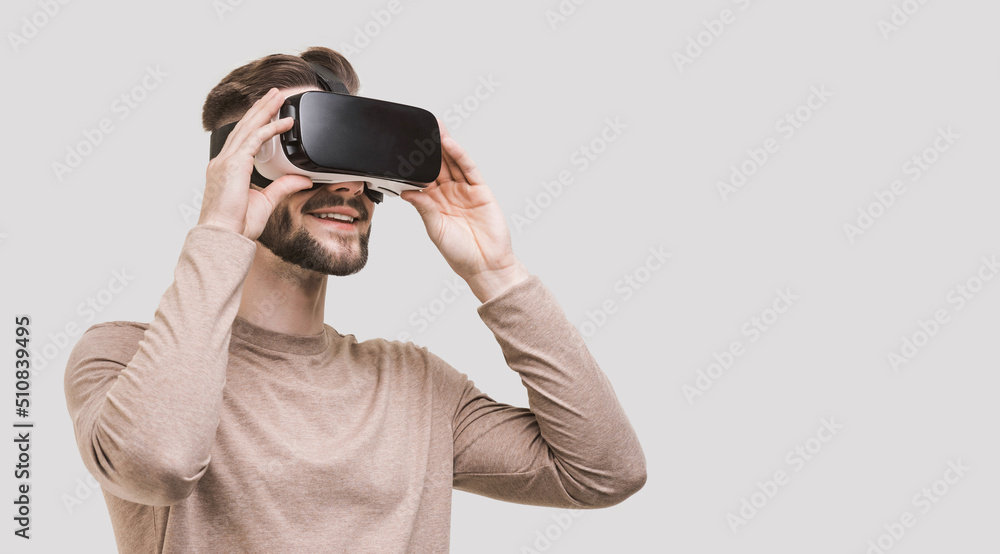 Young man using virtual reality headset isolated on gray background. VR, future, gadgets, technology concept Young man using virtual reality headset isolated on gray background. VR, future, gadgets, technology concept