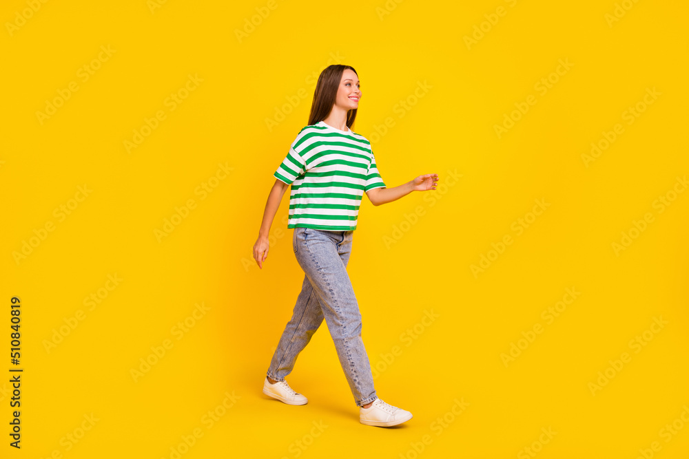 Full length profile photo of cheerful nice girl walking look empty space isolated on yellow color background Full length profile photo of cheerful nice girl walking look empty space isolated on yellow color background