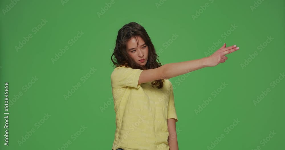 Cool young girl make gun gesture, searching for target shooting with hand pistol to camera on chromakey green background Cool young girl make gun gesture, searching for target shooting with hand pistol to camera on chromakey green background