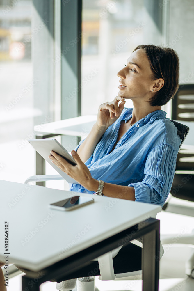 Woman sitting at the office desk and using tablet Woman sitting at the office desk and using tablet