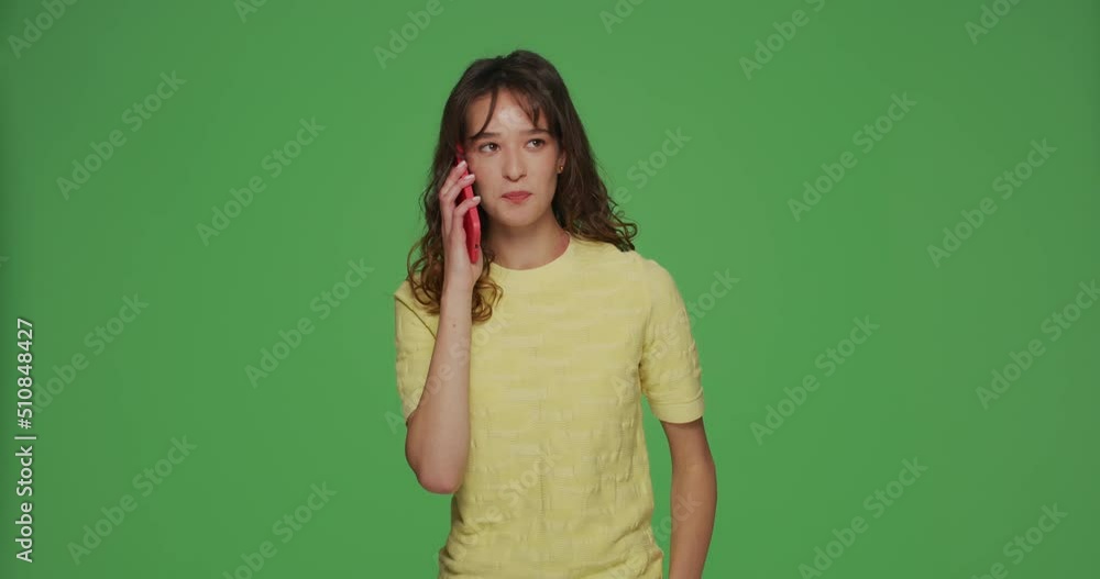 Friendly sociable young girl holds mobile phone, answers call, talking with friends on chromakey green studio background Friendly sociable young girl holds mobile phone, answers call, talking with friends on chromakey green studio background