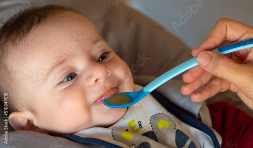 Fotografía Close-up of a few months old baby starting weaning by eating a fruit puree