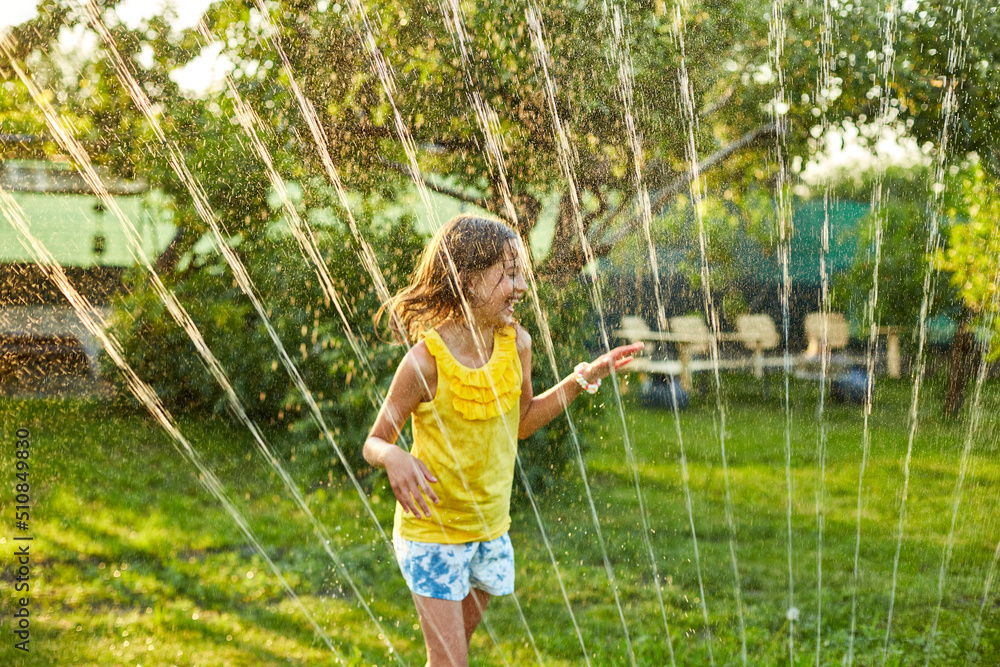 Happy kid girl playing with garden sprinkler run and jump, summer - obrazy, fototapety, plakaty 