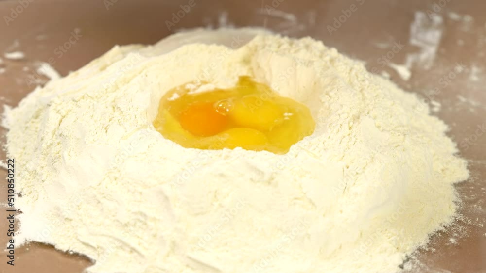 Kneading dough close view. Adding eggs in flour. Flour on glossy table. Prepare dough. Homemade cooking for pizza or cake. High quality 4k video. Kneading dough close view. Adding eggs in flour. Flour on glossy table. Prepare dough. Homemade cooking for pizza or cake. High quality 4k video.