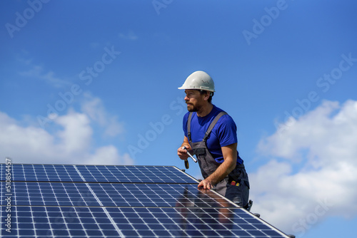 Man worker installing solar photovoltaic panels on roof, alternative energy concept.