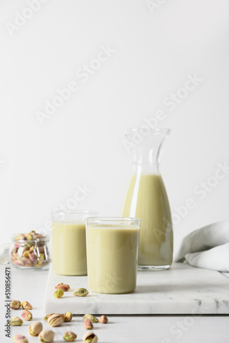 Pistachio nutty milk in glasses and pistachios on white background. Vegan lactose free milk replacer. Vertical. Close up.