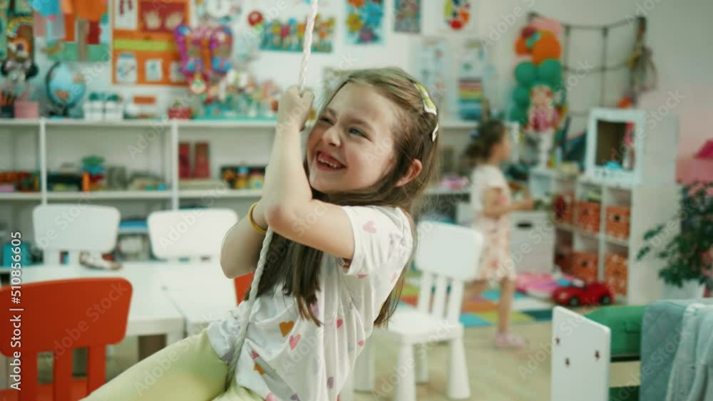 Slow motion shot of Little girl swinging on a swing in kindergarten Slow motion shot of Little girl swinging on a swing in kindergarten