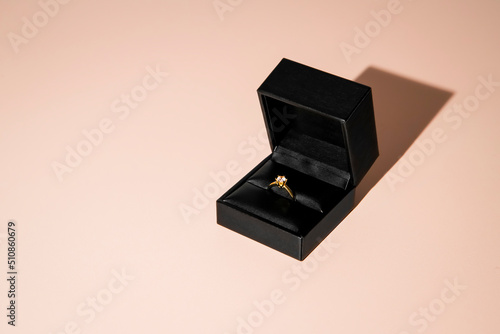 Golden engagement ring in black box with jewel. Marriage Proposal ring with a single brilliant.