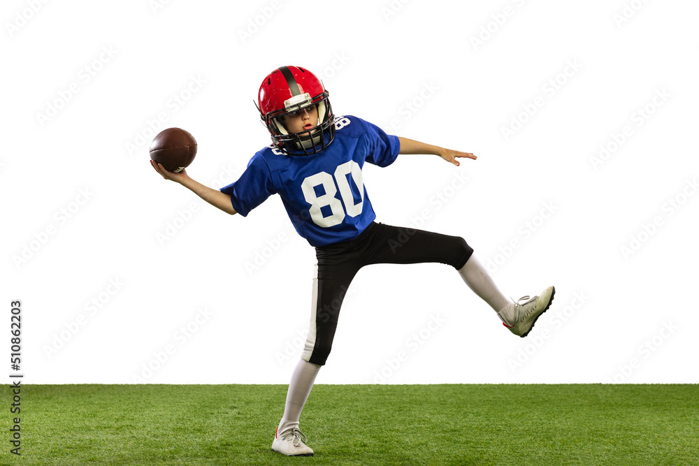 Sportive little boy in sports uniform and equipment playing american football isolated on white background with green grass flooring. Concept of sport, movement, achievements. Sportive little boy in sports uniform and equipment playing american football isolated on white background with green grass flooring. Concept of sport, movement, achievements.