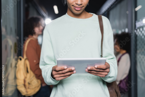 cropped view of african american student with digital tablet on blurred background.
