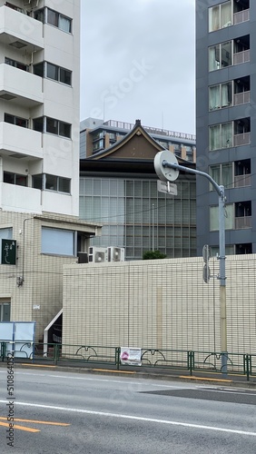 Traditional temple house rooftop peeking between the new modern buildings, cityscape Tokyo year 2022 June 14th