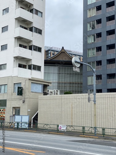 Traditional temple house rooftop peeking between the new modern buildings, cityscape Tokyo year 2022 June 14th