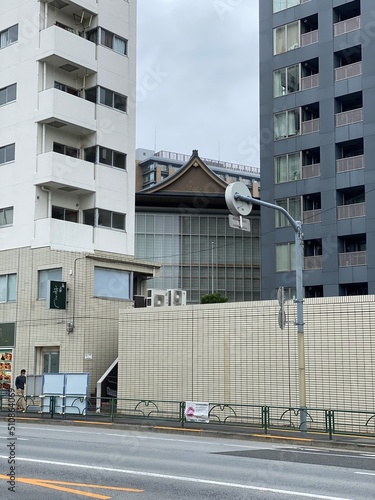 Traditional temple house rooftop peeking between the new modern buildings, cityscape Tokyo year 2022 June 14th