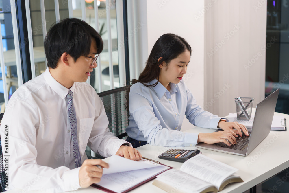 Business concept, Two business colleague checking financial data and typing report on laptop Business concept, Two business colleague checking financial data and typing report on laptop
