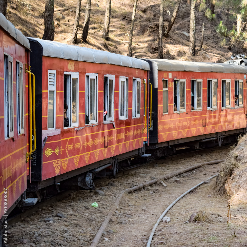 Obraz premium Toy Train moving on mountain slopes, beautiful view, one side mountain, one side valley moving on railway to the hill, among green natural forest. Toy train from Kalka to Shimla in India