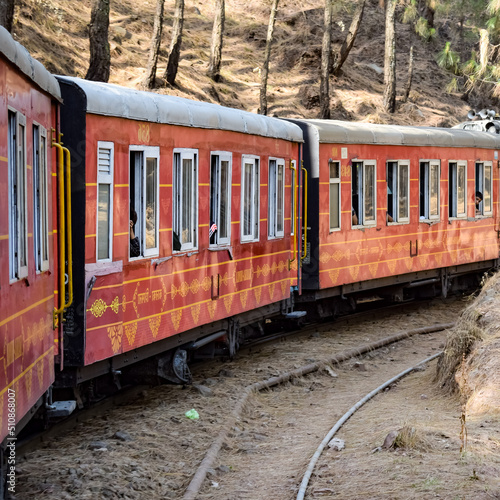 Toy Train moving on mountain slopes, beautiful view, one side mountain, one side valley moving on railway to the hill, among green natural forest. Toy train from Kalka to Shimla in India