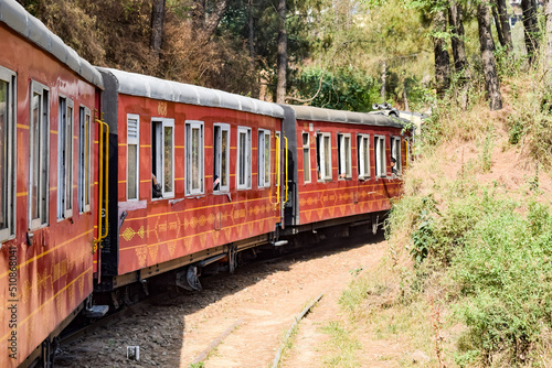 Toy Train moving on mountain slopes, beautiful view, one side mountain, one side valley moving on railway to the hill, among green natural forest. Toy train from Kalka to Shimla in India