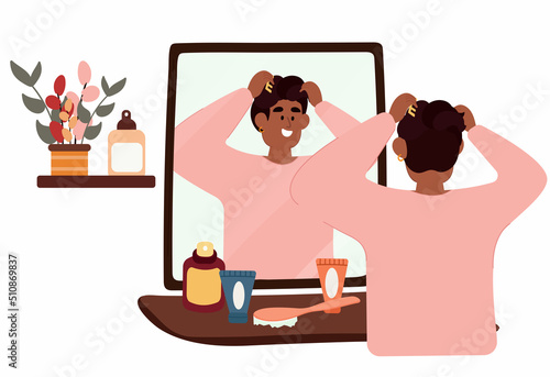 A black man stands in front of a mirror and does his hair. Daily morning routine of a man.