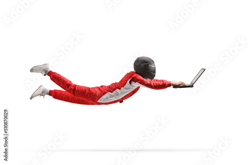 Motorsport racer with a helmet flying and working on a laptop computer