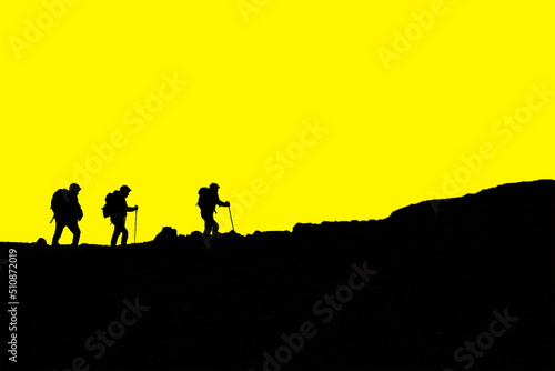 Silhouette escursionisti che camminano in montagna cielo giallo 