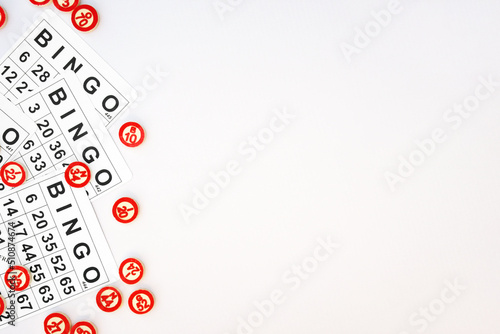 Many wooden chips with numbers and cards for a board game of bingo or lotto on a light background.