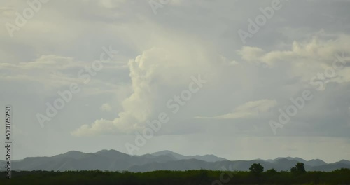 Clouds that were forming in the sky flowed over the top of the mountain.