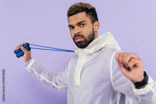 bearded african american man holding skipping rope isolated on purple.