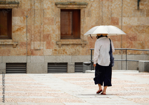 Woman walking in the street with a sun umbrella