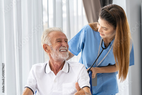 Man being cared for by a private Asian nurse at home suffering from Alzheimer's disease to closely care for elderly patients photo