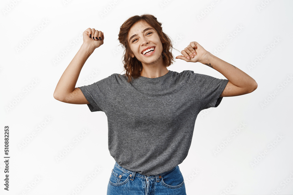 Portrait of beautiful happy girl smiling and dancing with raised arms, having fun, posing pleased against white background Portrait of beautiful happy girl smiling and dancing with raised arms, having fun, posing pleased against white background
