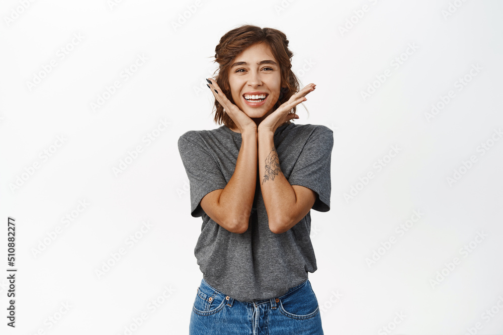 Adorable young woman with perfect facial skin without makeup, smiling white teeth, showing her face and laughing satisfied, standing over white background Adorable young woman with perfect facial skin without makeup, smiling white teeth, showing her face and laughing satisfied, standing over white background