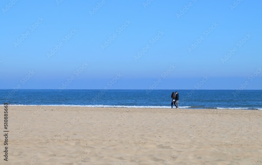 Pareja caminando por la playa de la Malvarrosa en Valencia, España. Playa en una suave mañana de invierno junto al puerto deportivo de Valencia.