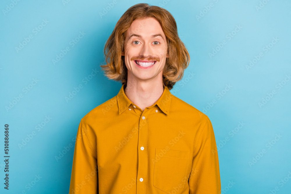 Portrait of attractive cheerful red-haired guy wearing mustard shirt isolated over bright blue color background Portrait of attractive cheerful red-haired guy wearing mustard shirt isolated over bright blue color background